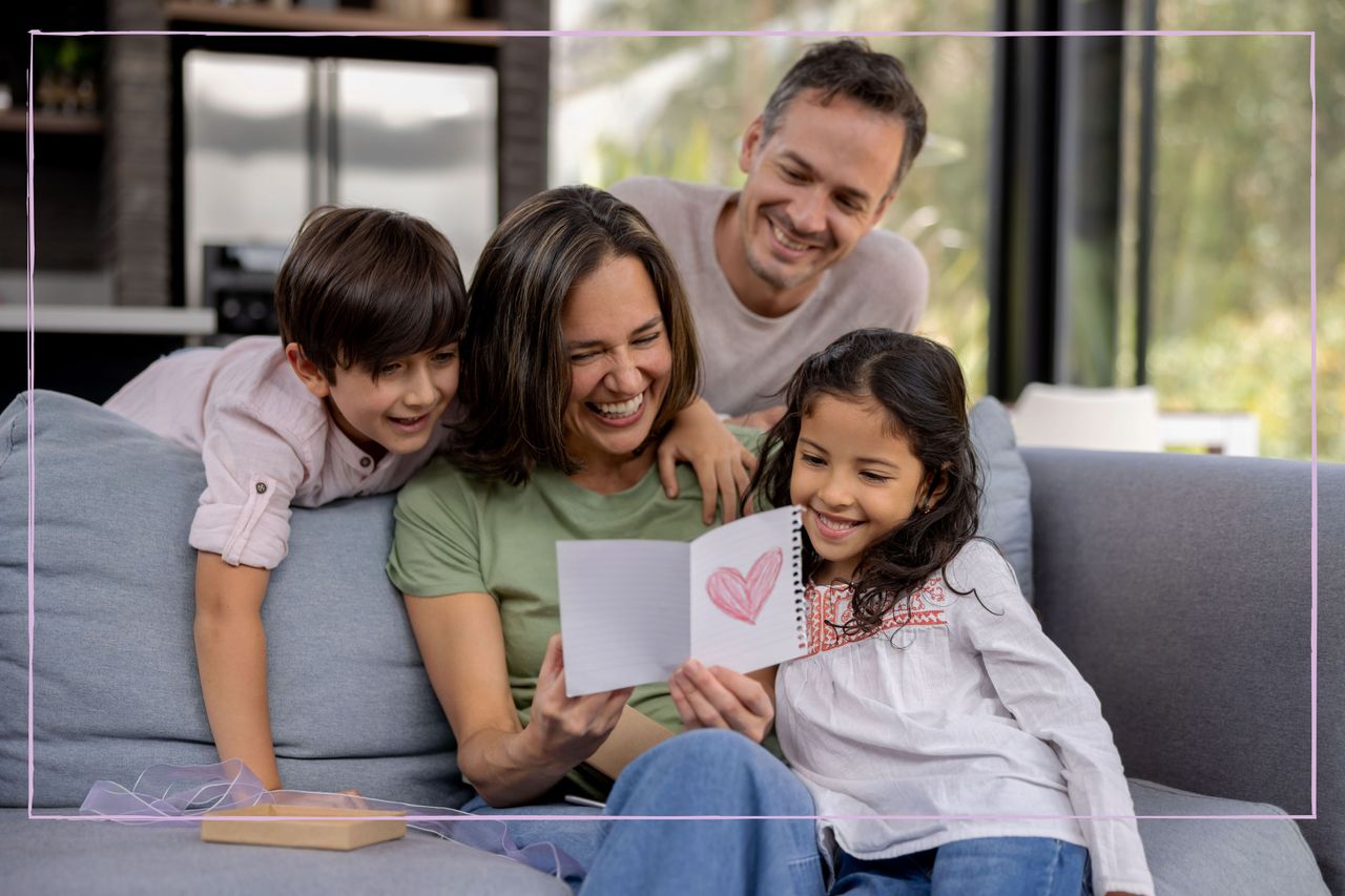 Family gathered round mum on the sofa as she reads Valentine&#039;s Day card