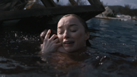 Lisa holding her newborn baby against her shoulder while in floodwaters in Netflix's Thrash