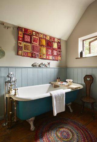 blue freestanding bath in bathroom with tapestry and panelling