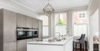 Contemporary white and gray kitchen with a statement chandelier to show how to make a kitchen look expensive on a budget with elegant lighting