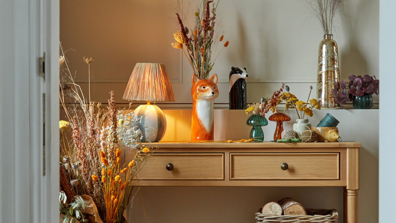 Neutral coloured striped lamp surrounded by table of vases of dried flowers