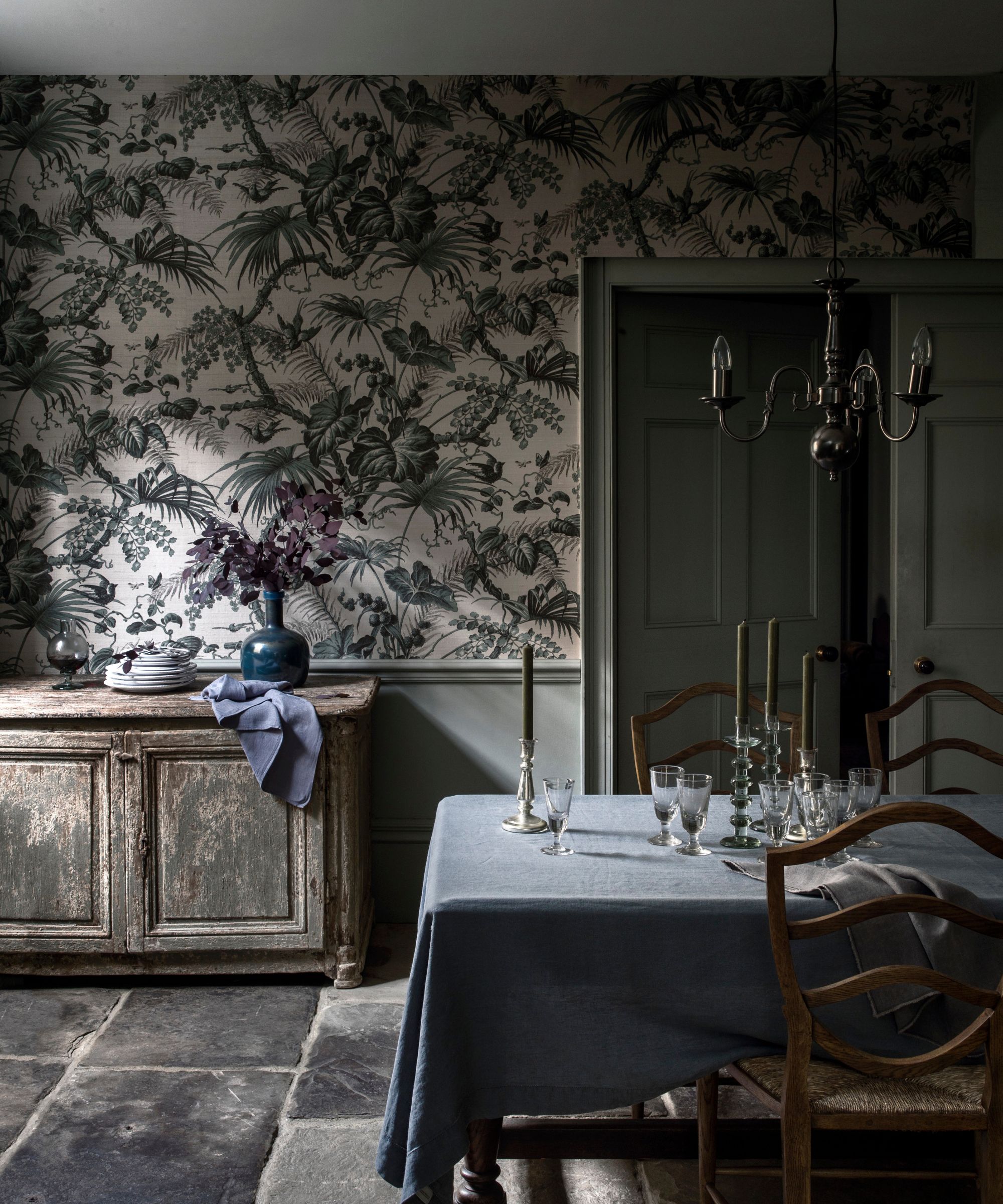 Moody dining room with candles on the table and patterned wallpaper
