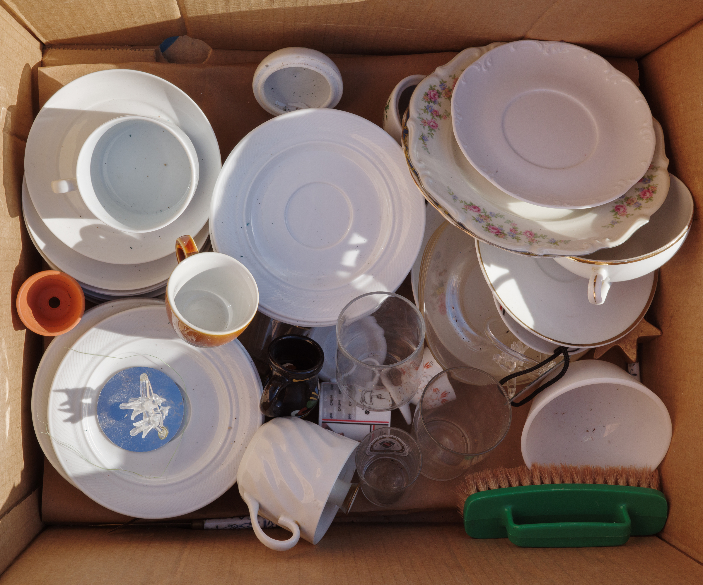 box of mismatched crockery, glasses and kitchen items