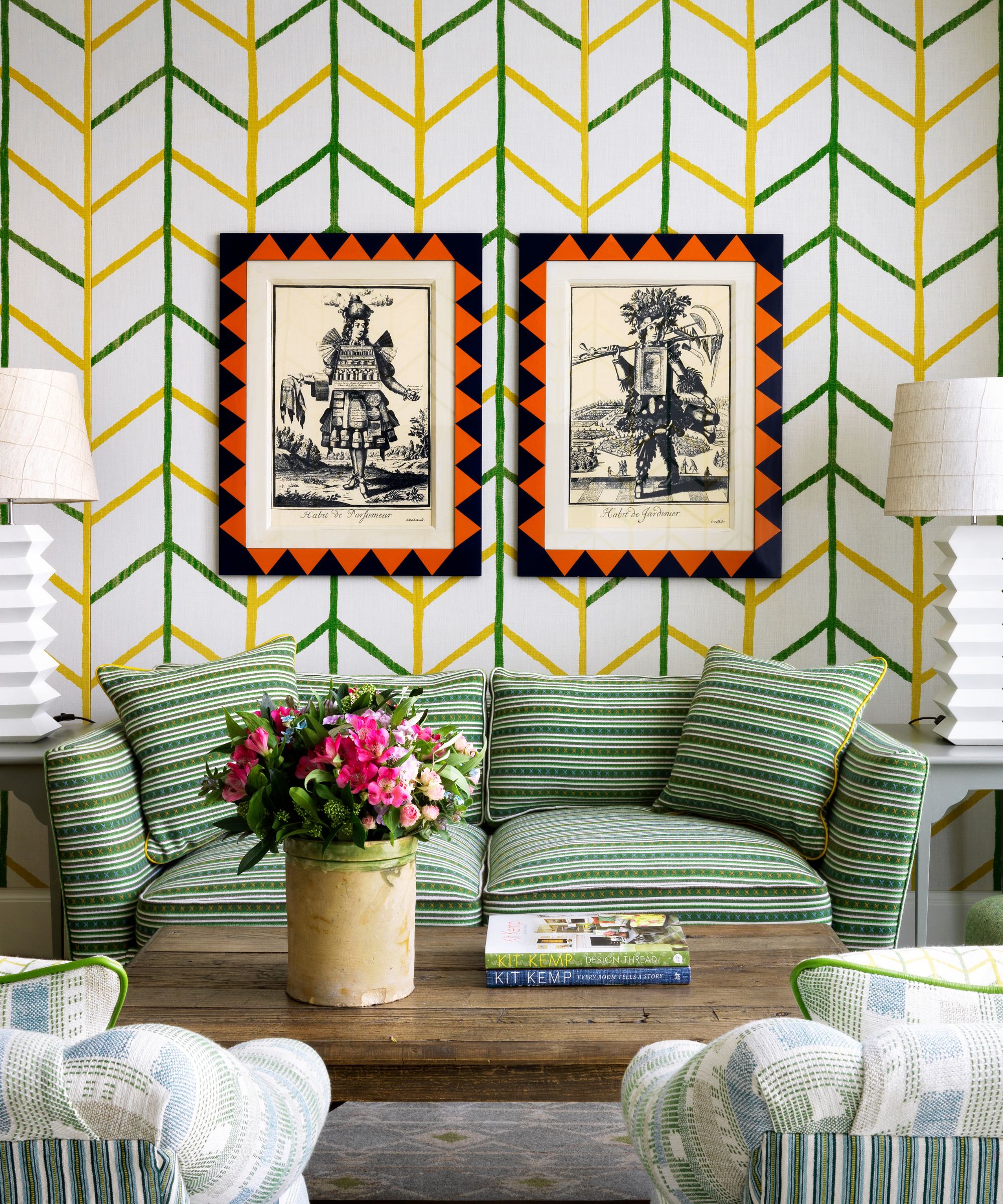 Living room with green and yellow wallpaper two prints above a green striped sofa