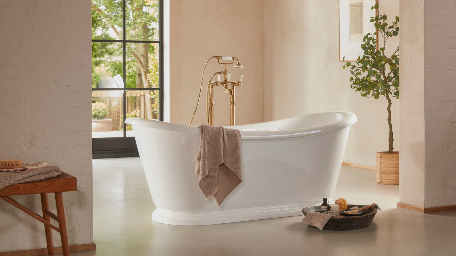 Freestanding bath with a windowed door behind and a towel draped over the side