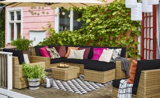 outdoor cushions on a rattan outdoor sofa on a cosy patio with a parasol and monochrome outdoor rug