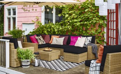 outdoor cushions on a rattan outdoor sofa on a cosy patio with a parasol and monochrome outdoor rug 