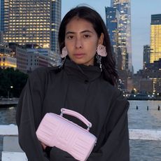 a woman wearing a black jacket and pink clutch bag