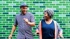 An older couple smile as they dance side by side.