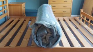 Mattress in a box vacuum packed and rolled up on a bed frame