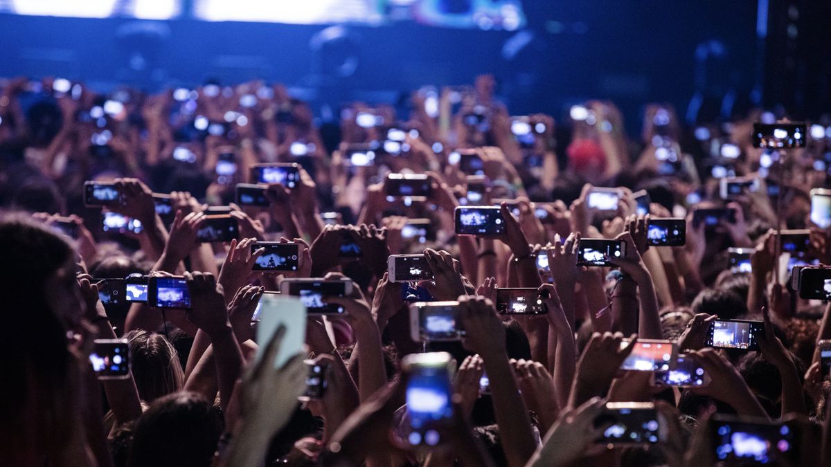 A crowd of people at a gig all filming