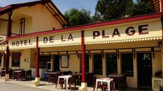 hotel de la plage in cap ferret, france with yellow and red wooden building and tables set outside