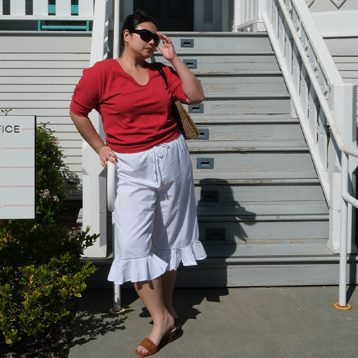 Marina wears red t-shirt, white long bloomers, wedges, and brown raffia bag. 