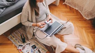 Woman at home unlocking external hard disk drive to print photos from laptop by using small portable printer