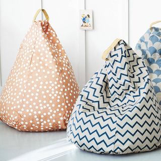 A pair of bean bags - one range with white polka dots and the other white with horizontal blue zigzag lines.