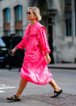 Woman wearing a neon pink parka dress in London