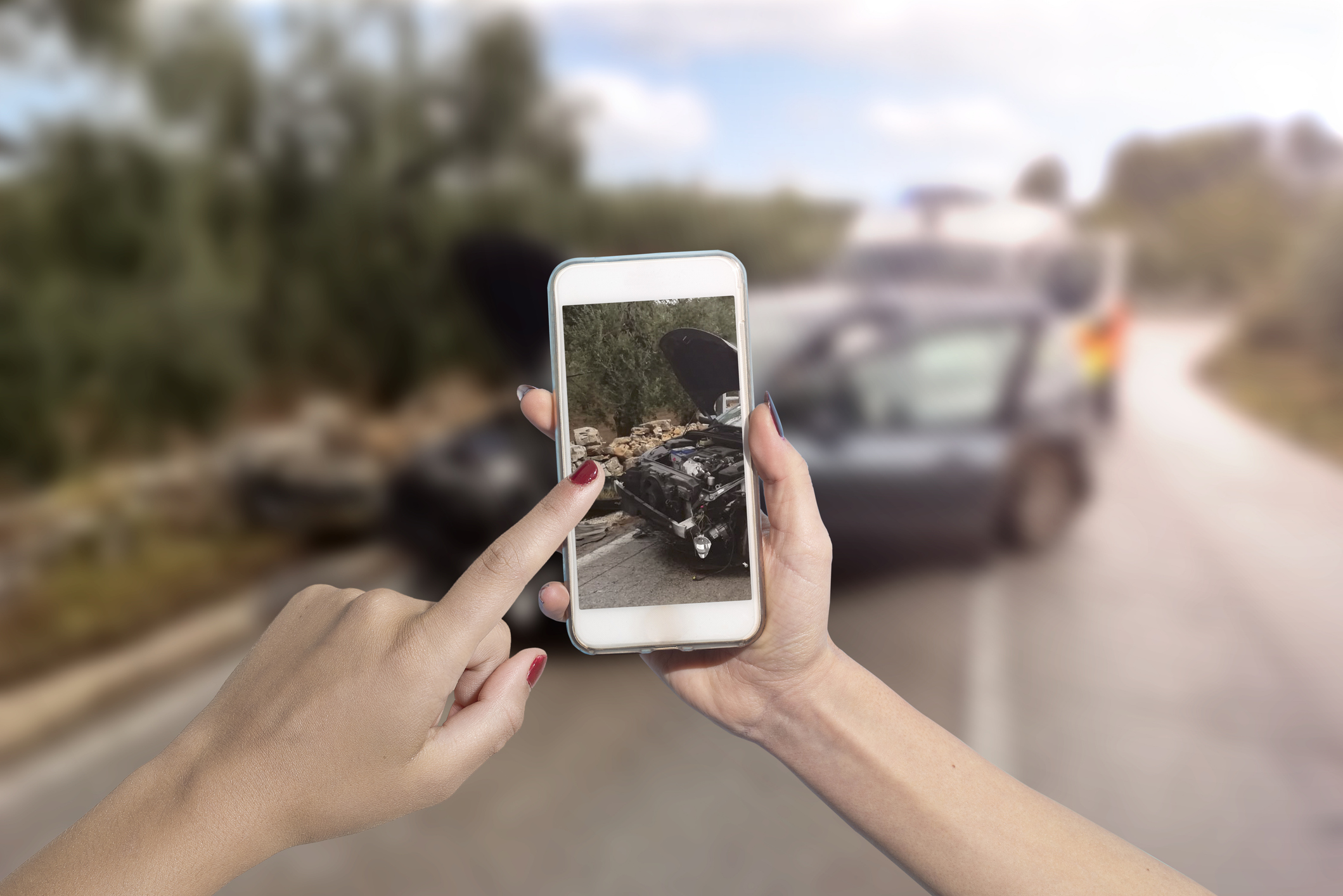 a person taking a picture on their phone of a car accident