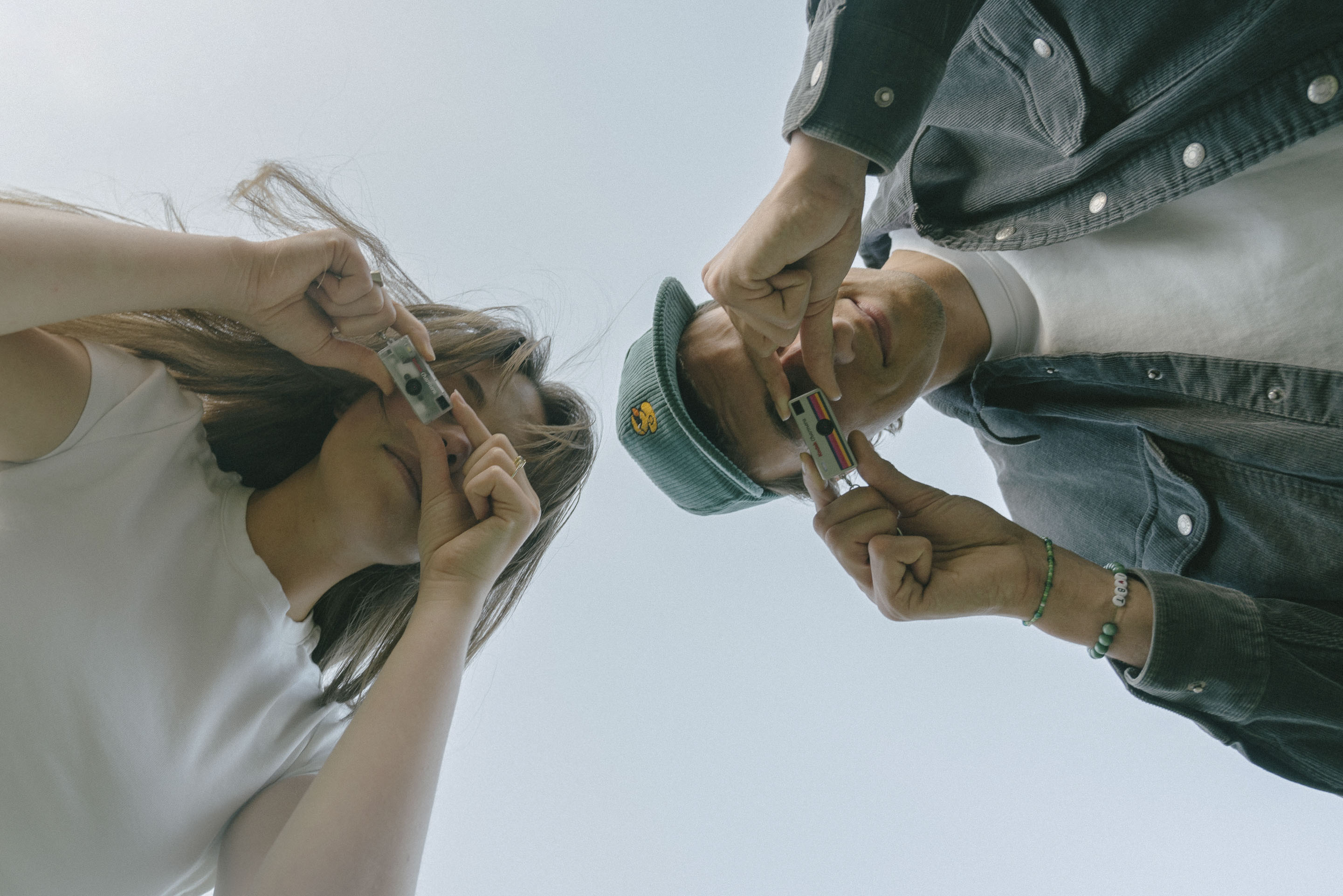 Two people holding a Kodak Charmera keyring camera up to their eye to take a picture