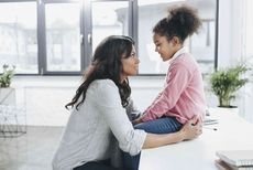 Mum kneeling in front of sitting daughter