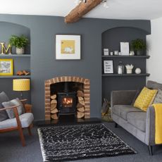 Wood burner in exposed brick fireplace in grey living room