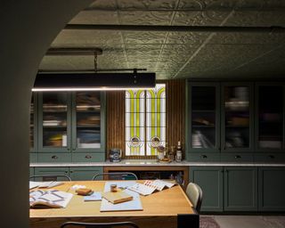 moody basement room with dark green cabinets and ceiling and wooden table