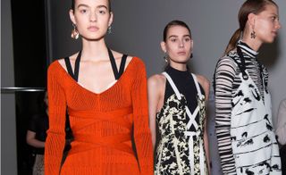 Female model wearing an orange sweater with black shoulder straps displayed, and two women in black and white patterned outfits