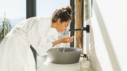 woman with acne washing her face