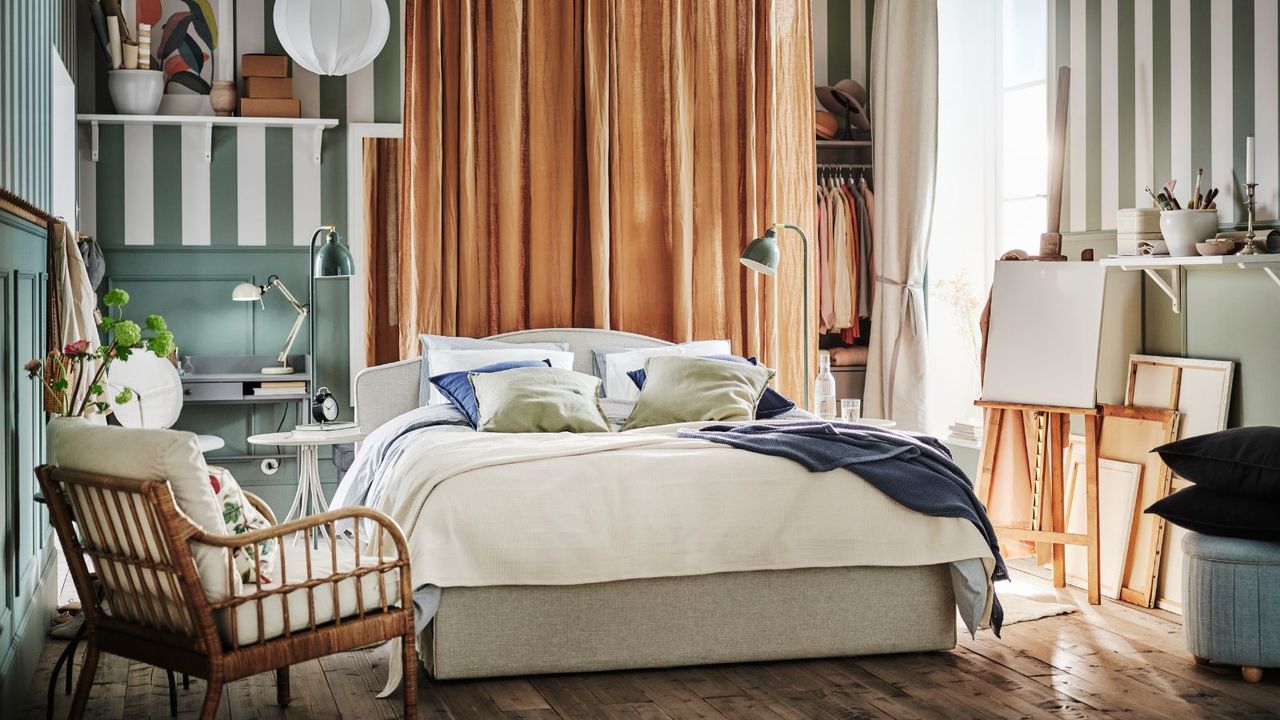 A white bed in the middle of a room with white and green wallpaper and brown curtains. 