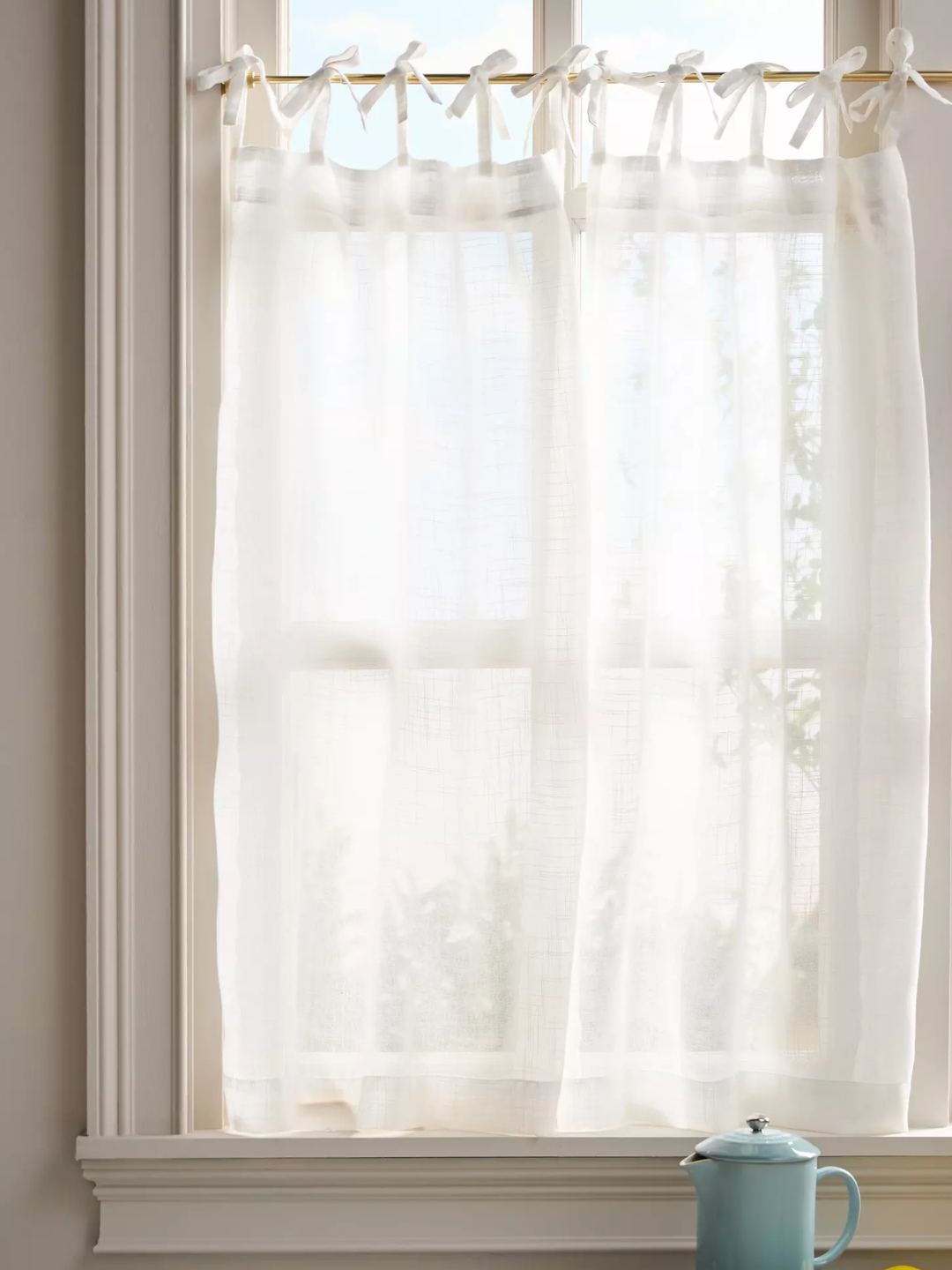 A set of sheer window curtains from Anthropologie with bow-tie tops