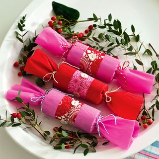 Christmas crackers in pink and red paper on place setting
