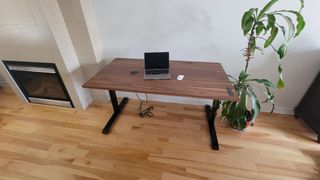 Ergonofis Sway desk next to a fireplace with a laptop and mouse on top.