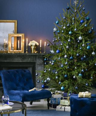 A blue Christmas decorating scheme with velvet armchair and foot stool