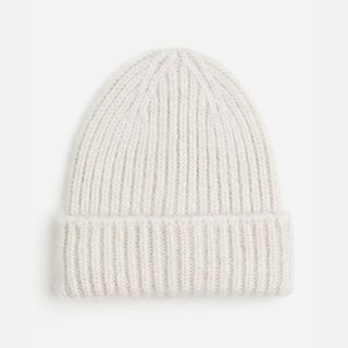 A cutout out of a cream ribbed beanie against a light grey background