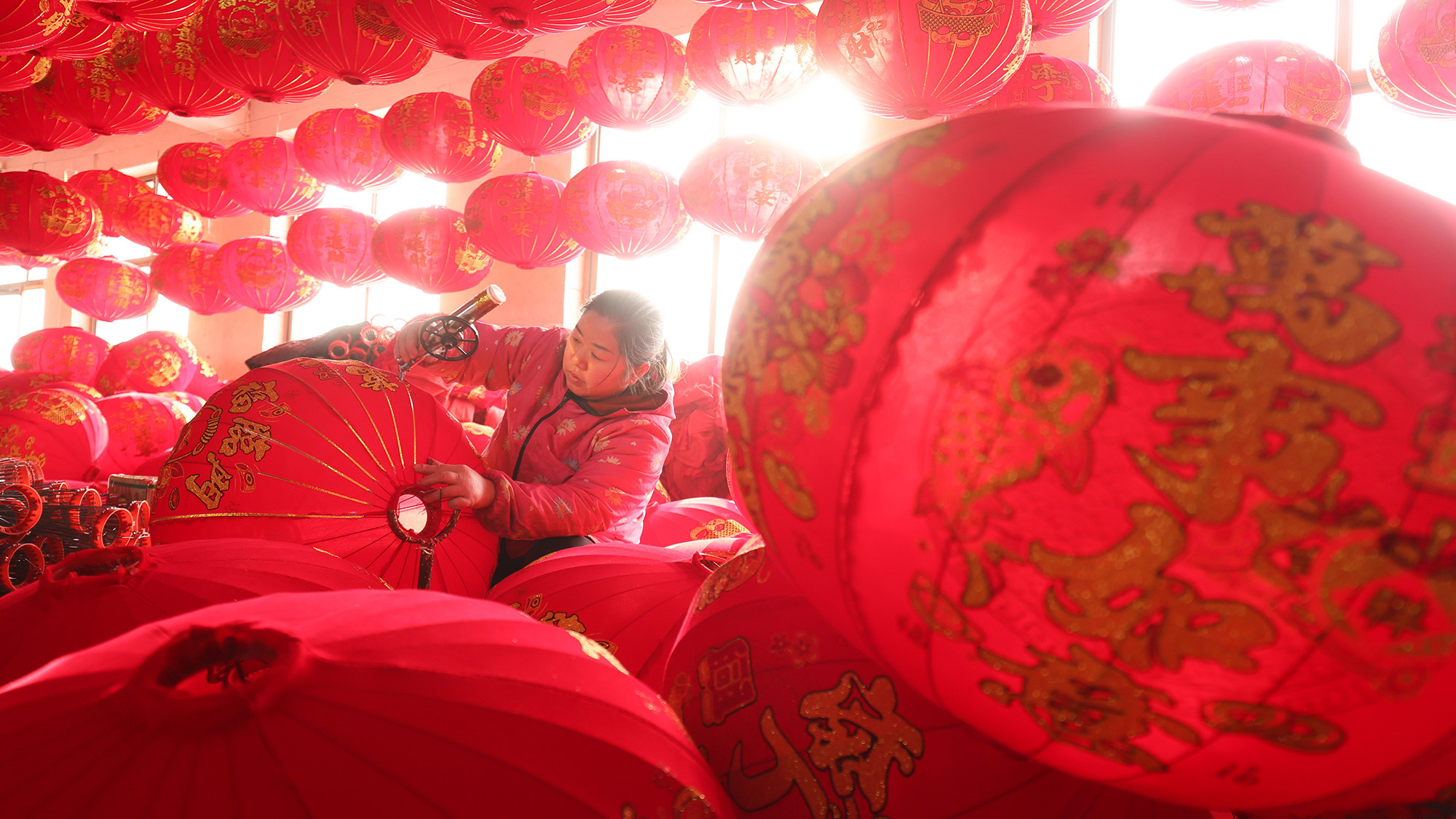 A worker makes red paper lanterns at a lantern factory in Tuntou Villiage, China