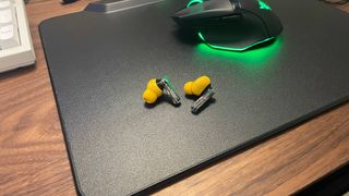 Nothing Ear (a) earbuds on a Razer HyperFlux mouse pad next to a Razer mouse
