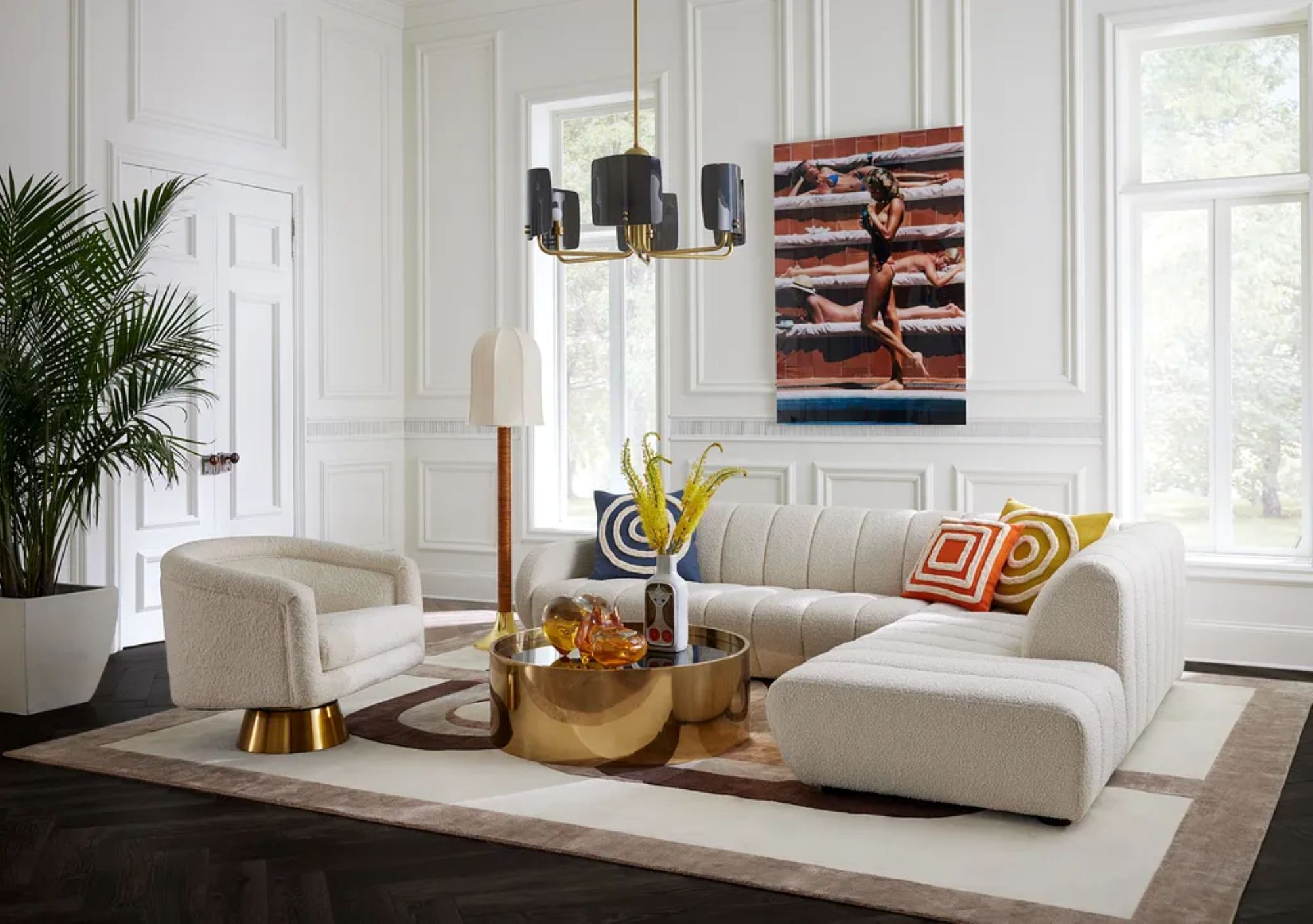 a white living room with a round metallic gold table and decorative throw pillows
