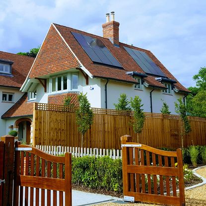 exterior of house with photovoltaic panels and wooden gate