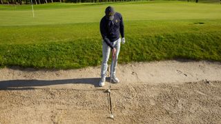 PGA pro John Howells drawing a 'T' shape in a bunker to help him hit better bunker shots