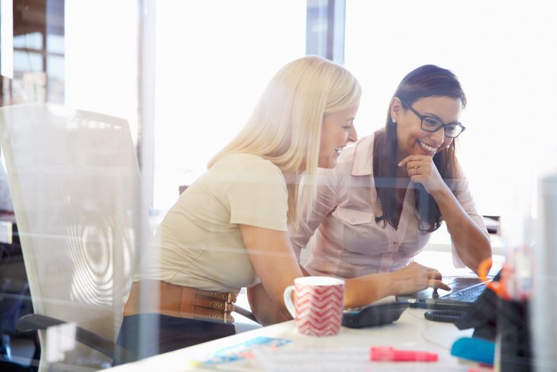 Two women work together at a computer