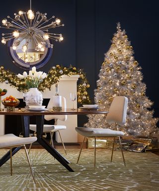 Christmas tree themes 2021 with a white tree decorated with gold and silver shiny baubles in a dark blue dining room