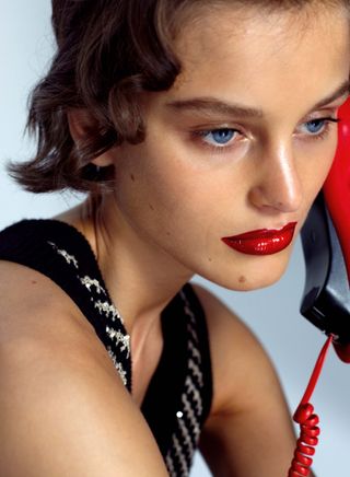 Girl with red lip shaped phone and bright red glossy Chanel lipstick