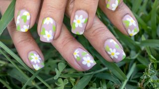 A woman's hands with lilac daisy nail art