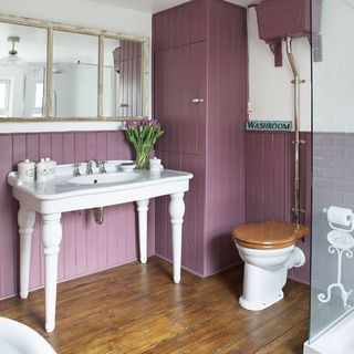 bathroom with purple coloured wall wooden flooring and cupboard