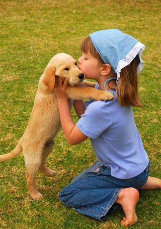 girl kissing a puppy