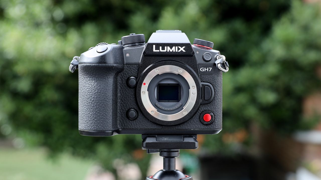 Panasonic Lumix GH7 on a tripod outside with some blurred green trees in the background