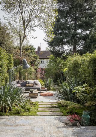 ideas for awkward shaped gardens: Long thin garden of Georgian townhouse with paved area with outdoor sofa and large, oversized standard anglepoise lamp Redecorated 3-bedroom Georgian townhouse in south London, home of Julia and Paul Thompson