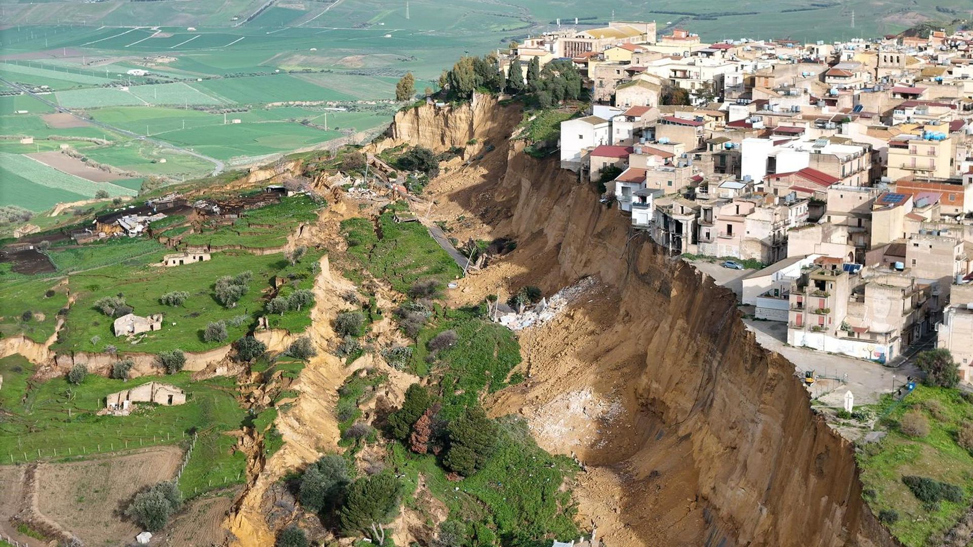 
                                Homes teeter on the edge of a muddy cliff after days of heavy rainfall caused a landslide in Niscemi, Sicily
                            