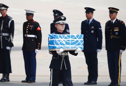 A soldier carries a box containing the remains of a U.S. soldier killed during the Korean War.