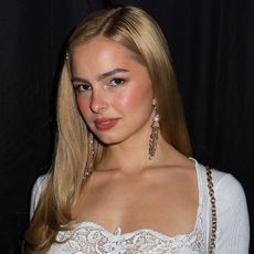Addison Rae wears a white lace-trim top and tassel earrings.