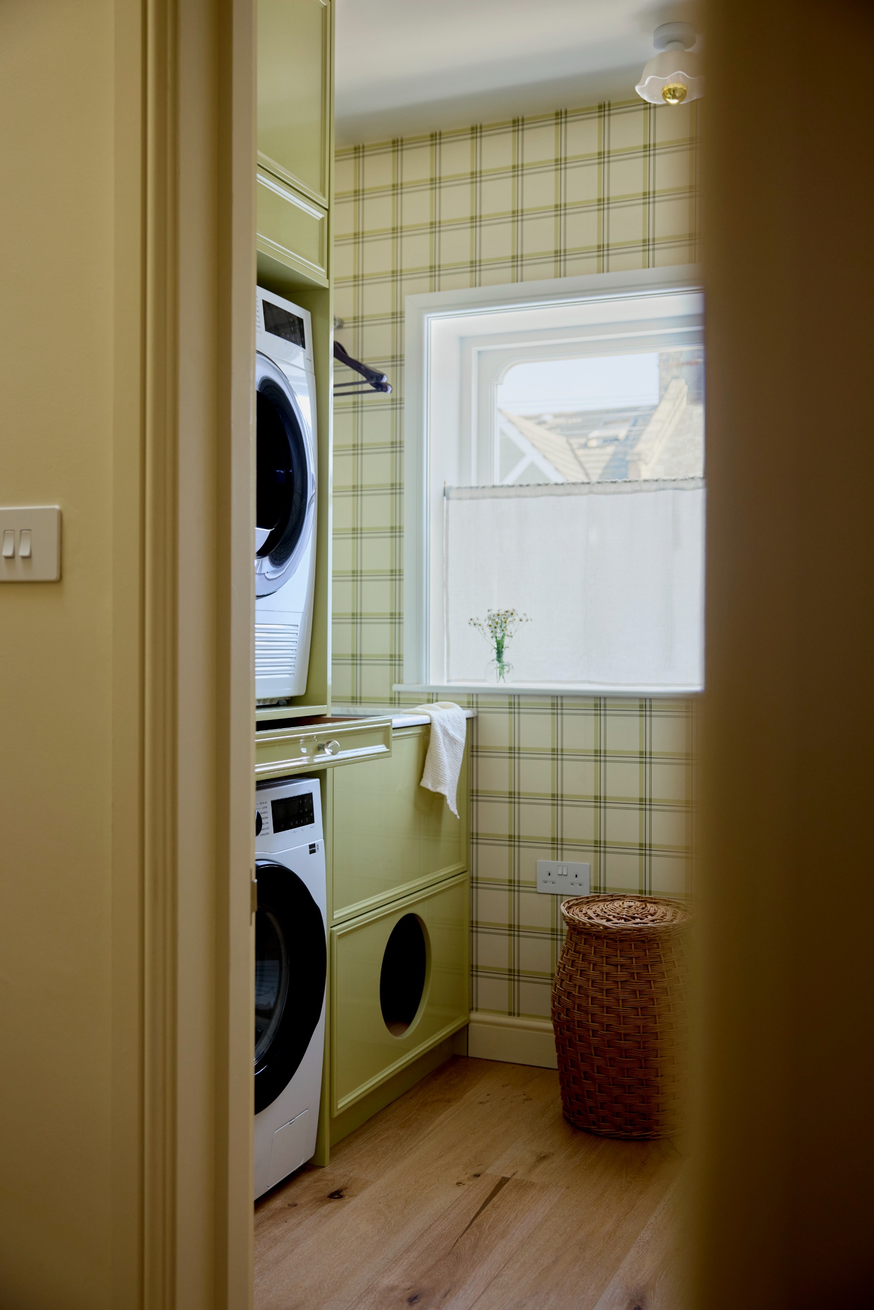 Utility room with glossy green bespoke cabinets and green check wallpaper